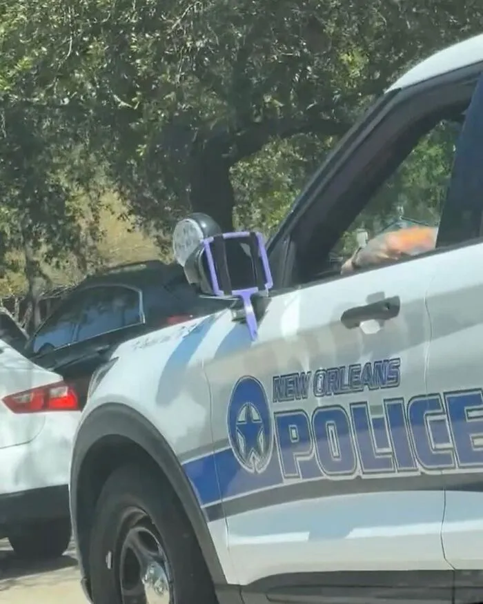 Police car in New Orleans with an unusual street find attached to the side mirror during a sunny day.