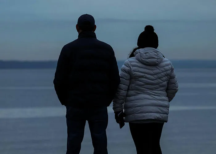 Two people wearing winter jackets stand by the water at dusk, capturing a moment with no filter family lore.