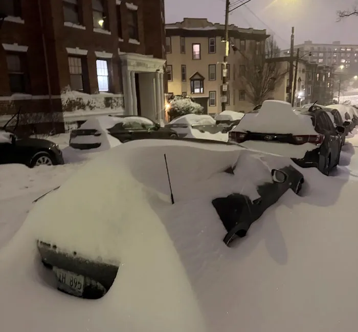 Cars buried under heavy snow on a city street during a severe snowstorm hitting the U.S. at night.