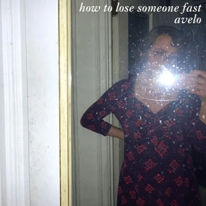 Person taking a mirror selfie with flash reflecting, wearing a patterned dress, featured on a hilariously bad album cover.