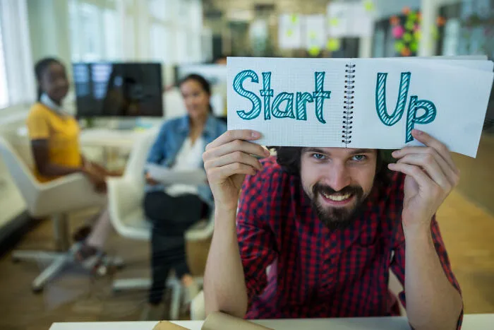 Man holding notebook with start up text in modern office, representing uplifting stories of progress and hope in America.