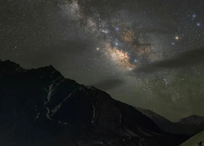 Starry night sky over dark mountainous landscape illustrating wacky stories told by 51 people hoping to be believed.
