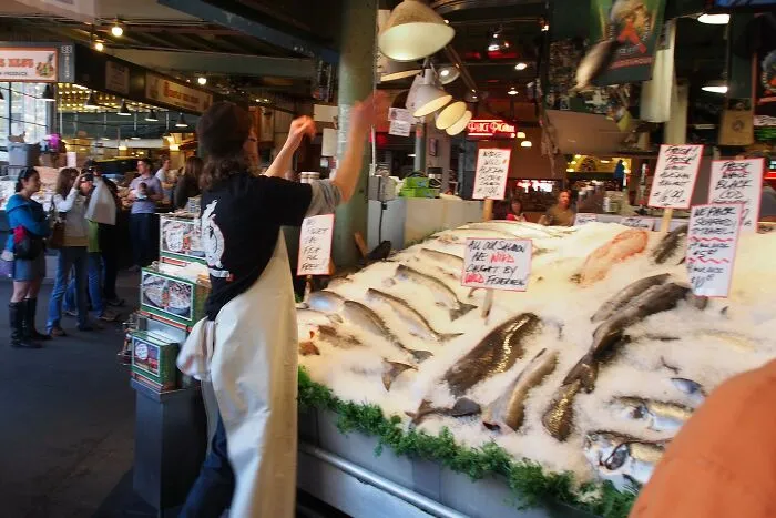 Busy fish market scene with vendor and tourists, illustrating disappointing tourist attractions locals still don’t get.