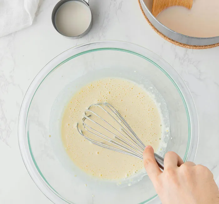 Hand whisking batter in a glass bowl on marble counter, people realized friends or family were very weird