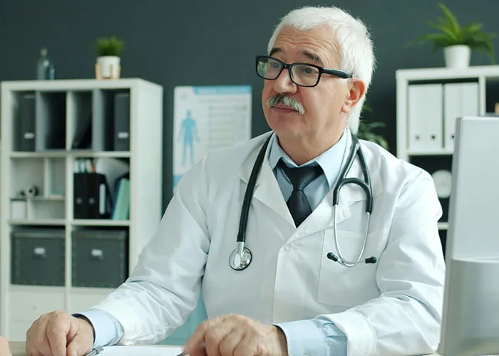 Senior male doctor wearing glasses and a stethoscope, sitting in an office discussing worst things medical professionals said
