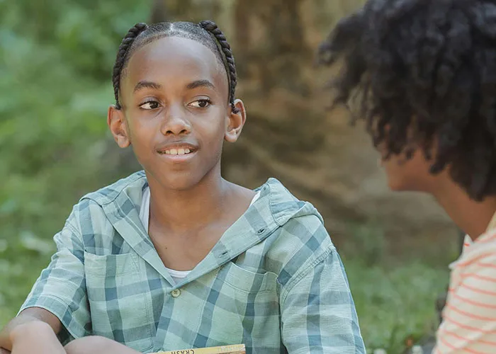 Two kids having a candid conversation outdoors, capturing the essence of kids with no filter sharing family lore.