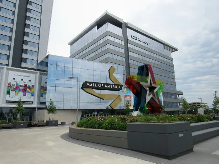 Mall of America entrance with colorful star sculpture and modern office buildings under a cloudy sky.