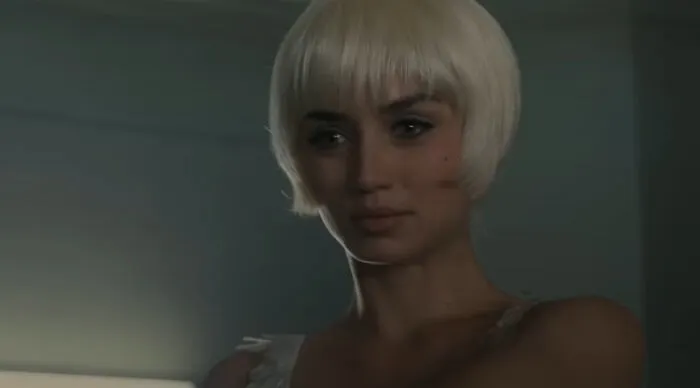 Young woman with platinum bob in dim room, contemplative expression, Would You Rather theme