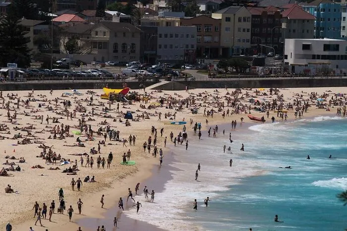 Crowded beach scene with many tourists enjoying the sand and water at a popular but disappointing tourist attraction.