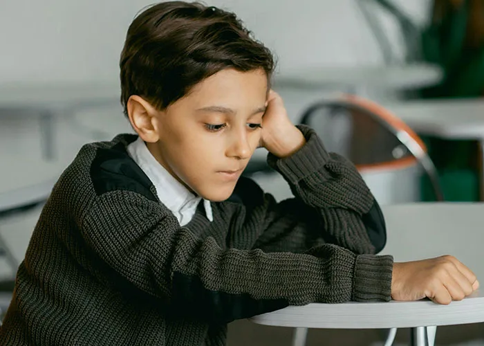 Young boy with no filter expression sitting at a table, reflecting on family lore in a casual indoor setting.