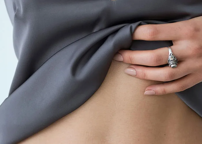 Close-up of a hand lifting fabric to reveal rare physiological traits on smooth skin in natural lighting.