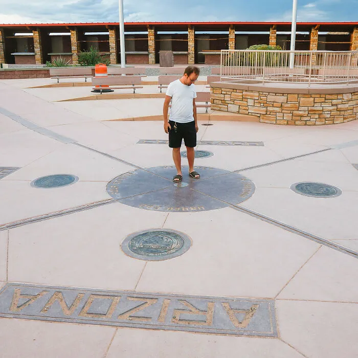 Man standing at a landmark with plaques and directions, one of many disappointing tourist attractions locals still don’t get.