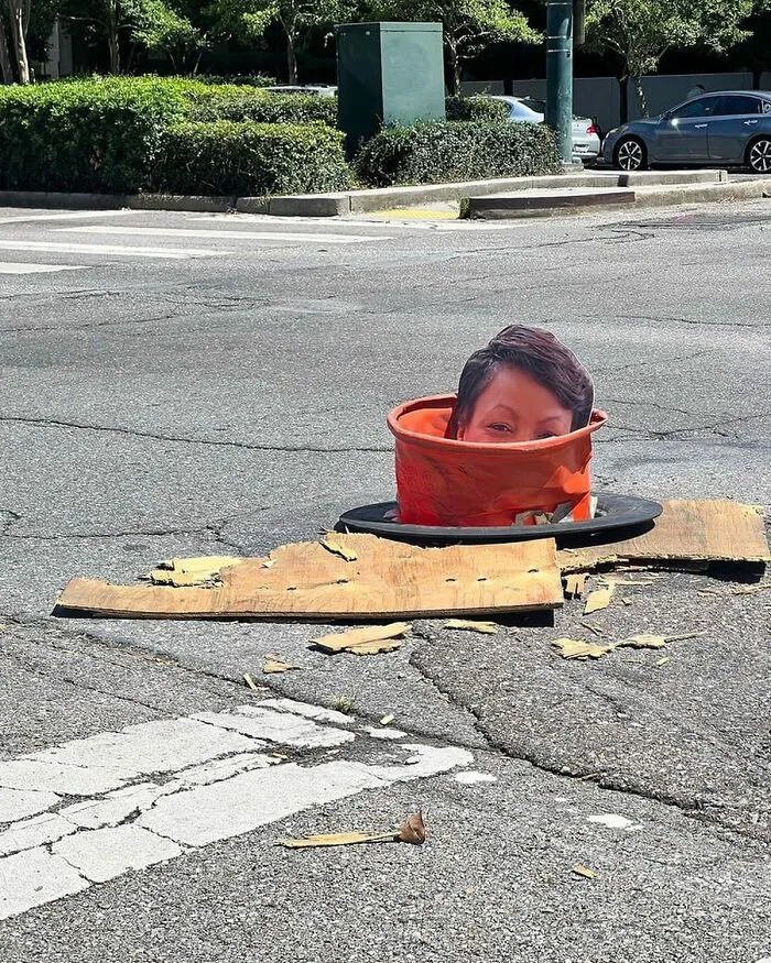 Person's head appearing inside an orange traffic cone in the street, one of the weirdest things found in the streets.