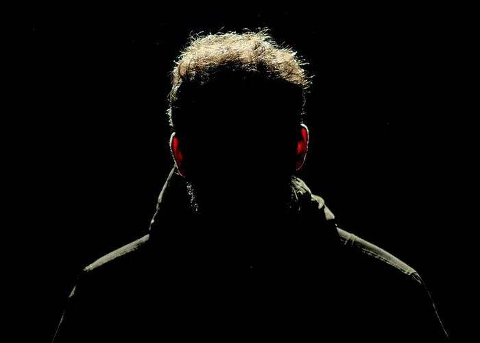 Silhouetted person with backlit curly hair in dark clothing, symbolizing wacky stories shared hoping someone will believe them.