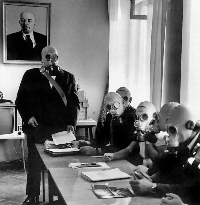 Group of people wearing gas masks in a vintage black and white photo, creating an odd and creepy atmosphere.