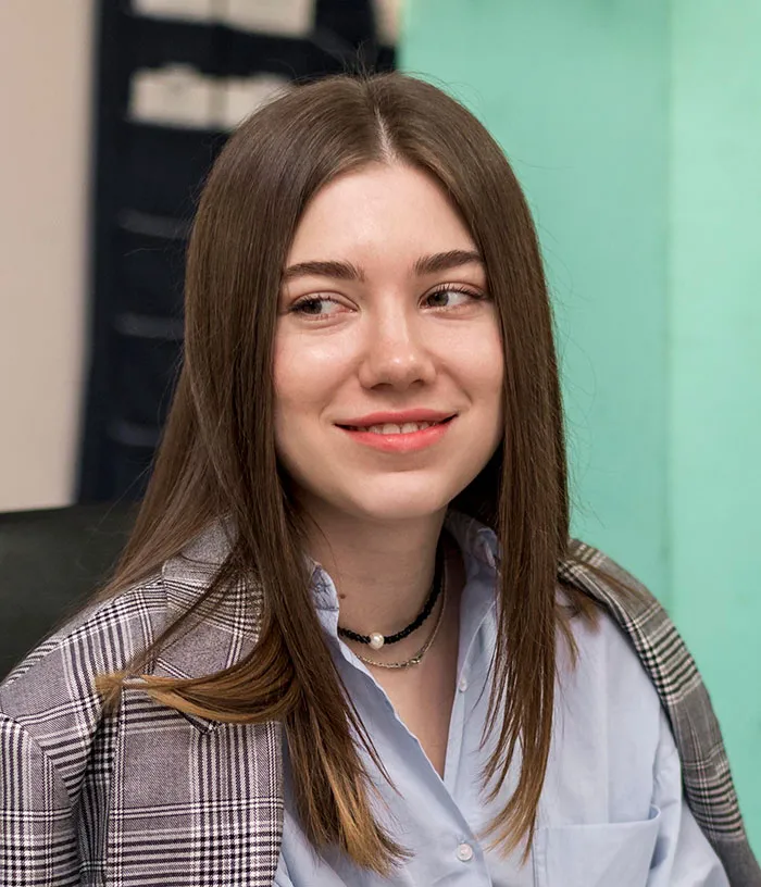 Young woman in a blazer and shirt smiling confidently during a job interview with recruiters about candidate mistakes.