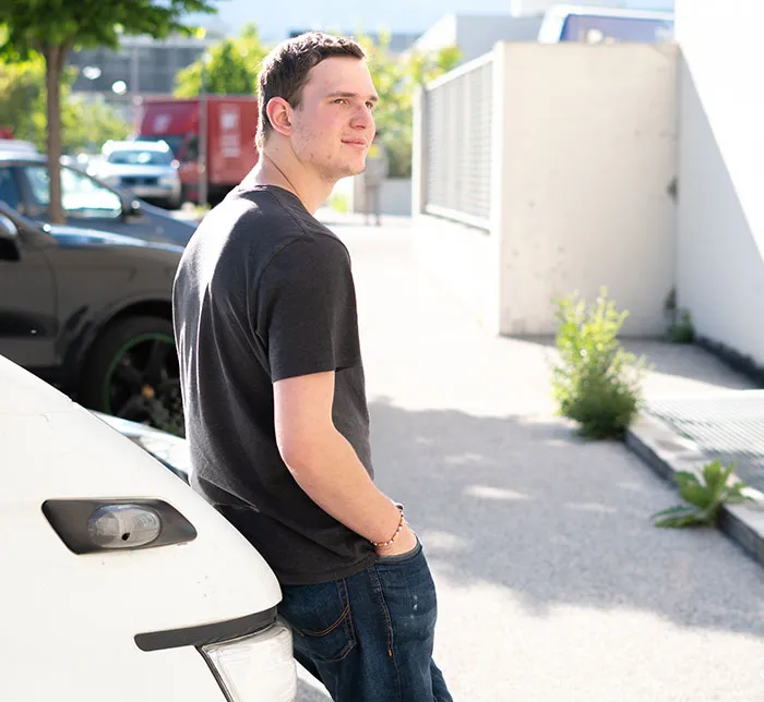 Young man in a black shirt leaning on a car outdoors, representing job candidates losing chances with recruiters instantly.