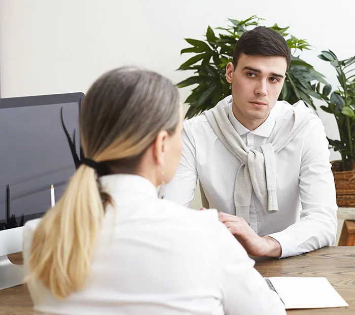 Young man in a job interview with recruiter discussing how job candidates instantly lost chances of getting hired.