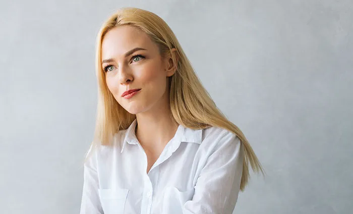 Blonde woman in a white shirt thoughtfully considering ways job candidates instantly lost chance of getting the job