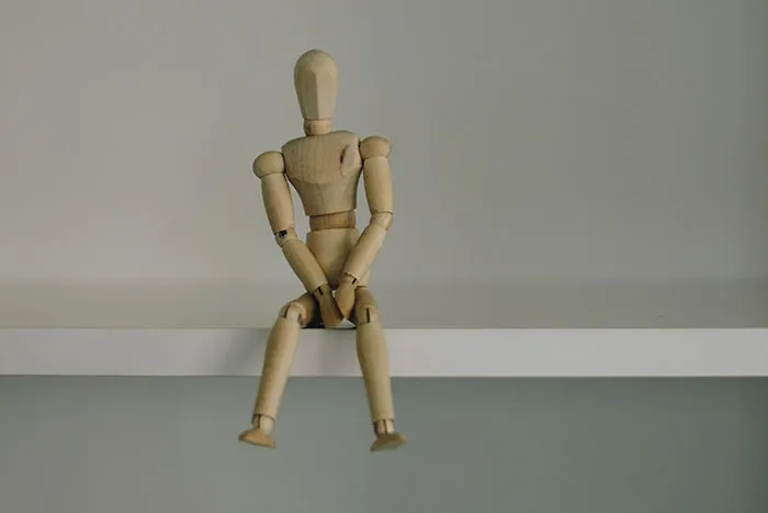 Wooden mannequin sitting on a white shelf, symbolizing men and thoughts women often want to understand.