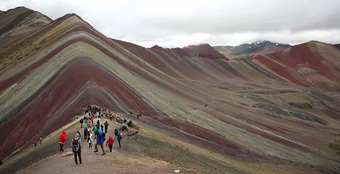 Tourists exploring colorful striped mountain ridges, a popular but disappointing tourist attraction locals avoid.