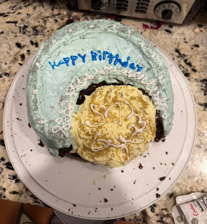 Partially broken birthday cake with messy frosting and uneven decoration, an example of ruined dessert.