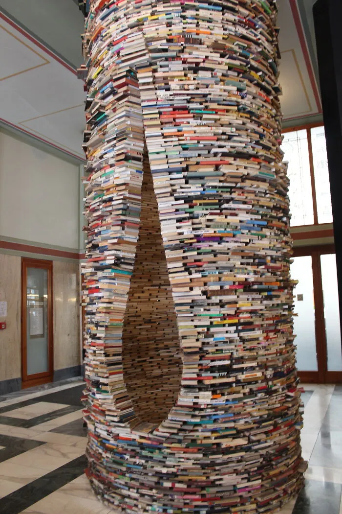 Large cylindrical sculpture made of stacked books inside a building, an unusual tourist attraction locals find disappointing.