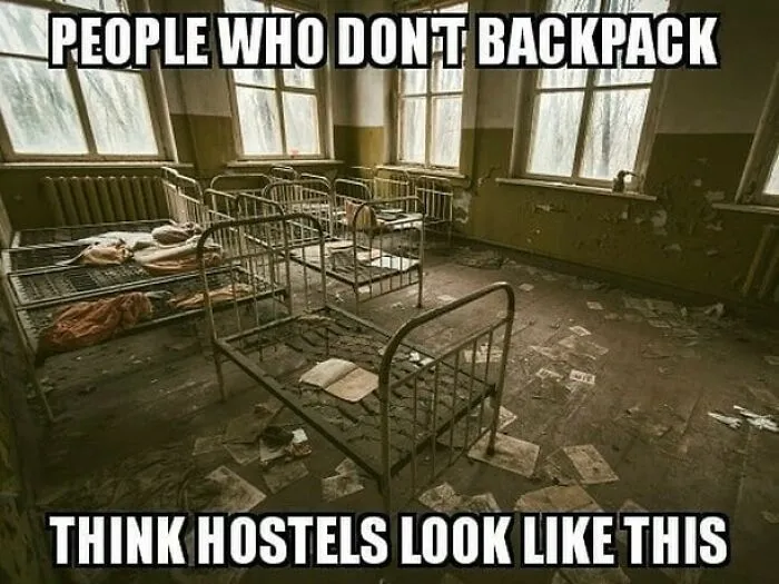 Old, rundown hostel room with rusty metal beds and scattered papers, illustrating a travel meme about hostels and backpacking.