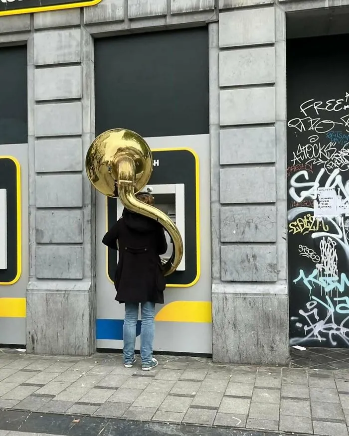 Person playing a large brass instrument on the streets of Brussels, showcasing one of the weirdest and most unhinged street scenes.