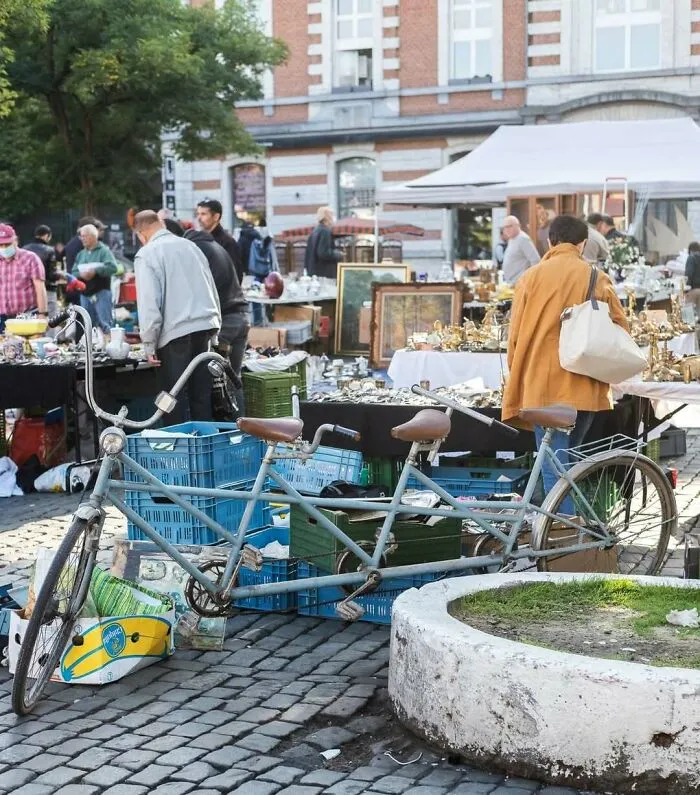 Tandem bicycle parked at a busy flea market, showcasing one of the weirdest and most unhinged things seen on Brussels streets.