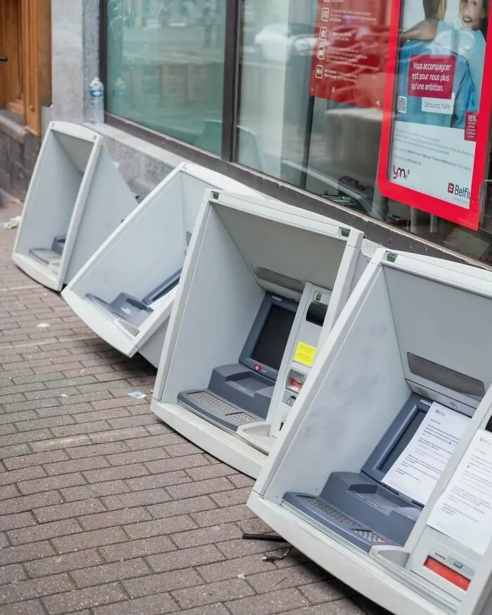 Several broken ATMs tipped over on a sidewalk, showcasing one of the weirdest and most unhinged things seen on the streets of Brussels.