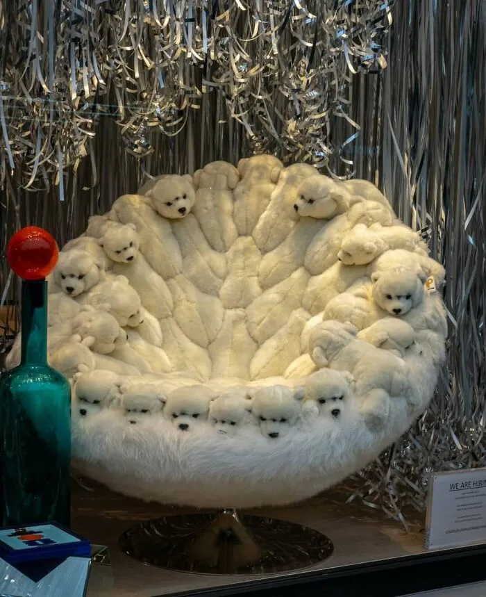 Furry chair with multiple white bear heads surrounded by shiny metallic streamers, a weird and unhinged streetscape in Brussels.