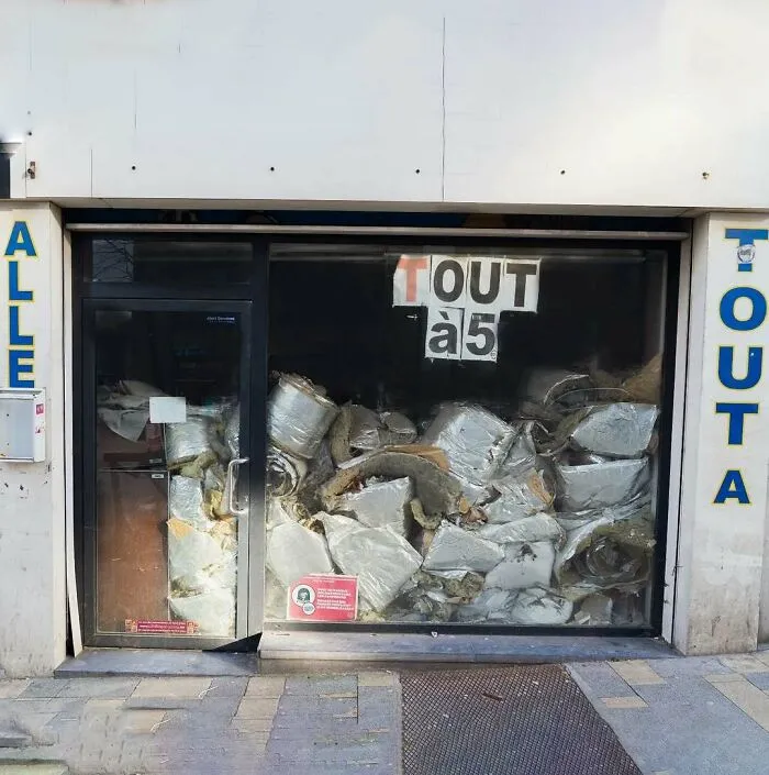 Storefront window in Brussels filled with random debris and insulation materials, showing one of the weirdest street scenes.