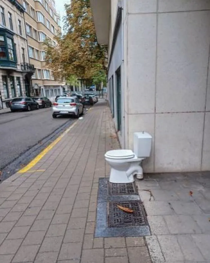 Toilet installed on a sidewalk as a weird and unhinged street sight in Brussels, blending urban elements with humor.