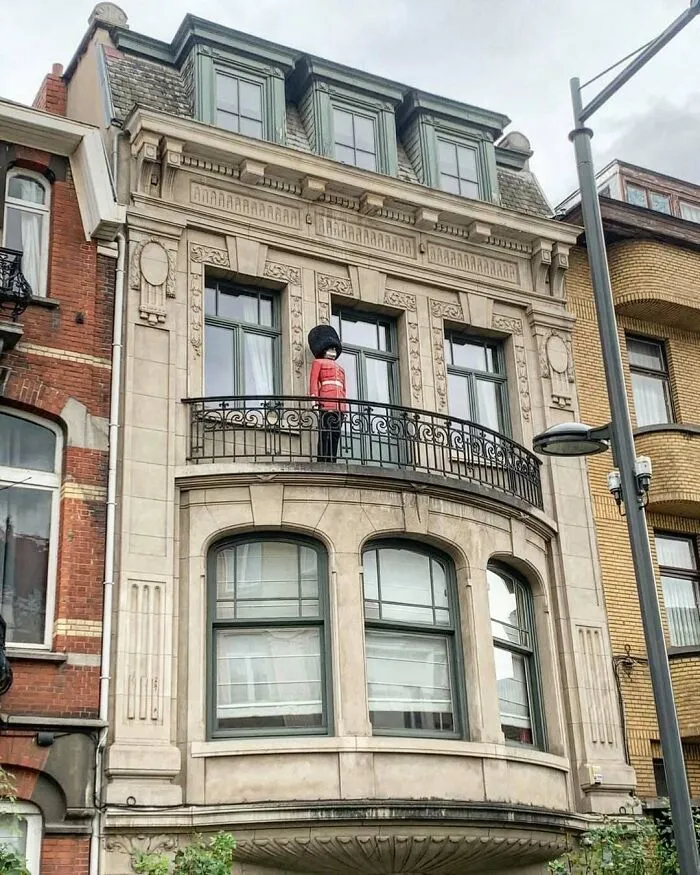 Toy soldier figure dressed in red on balcony railing of a historic Brussels building, one of the weirdest street sights.