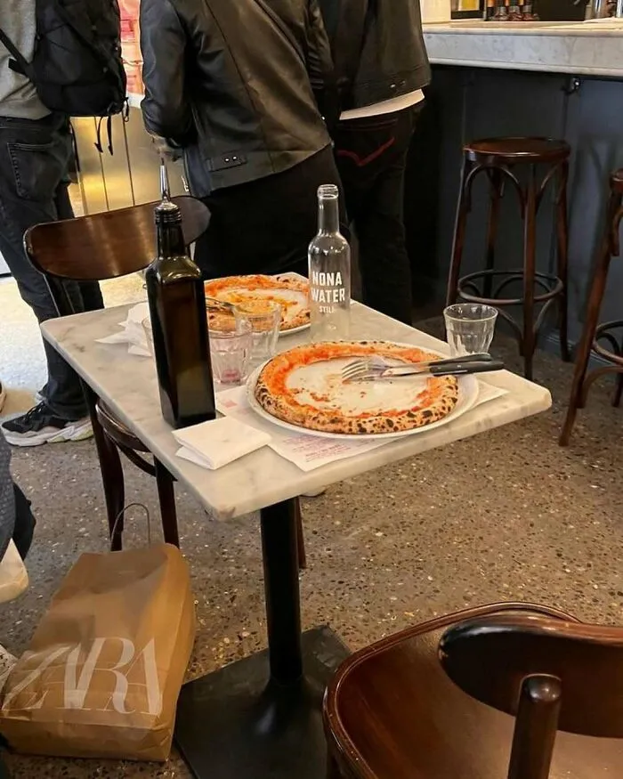 Empty pizza plates and water bottle on a café table, part of the weirdest and most unhinged things seen on Brussels streets.