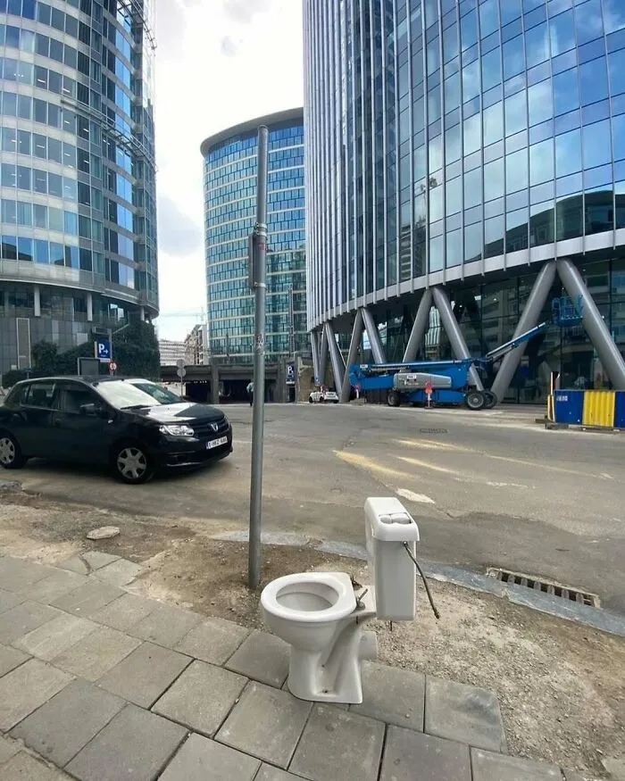 Toilet bowl bizarrely installed on a sidewalk among modern buildings, illustrating weirdest things seen on streets of Brussels.
