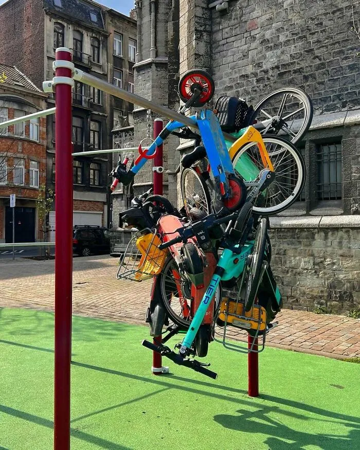 Unusual cluster of bikes and scooters tangled on street poles, showcasing one of the weirdest scenes in Brussels streets.