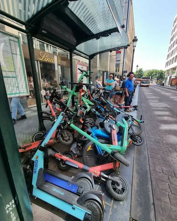 A chaotic pile of electric scooters clutter the sidewalk in Brussels, showcasing some of the weirdest and most unhinged street scenes.
