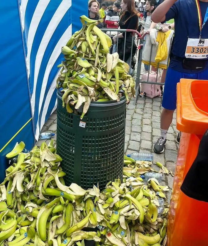 Overflowing trash bin with a large pile of banana peels on the streets of Brussels during an event.