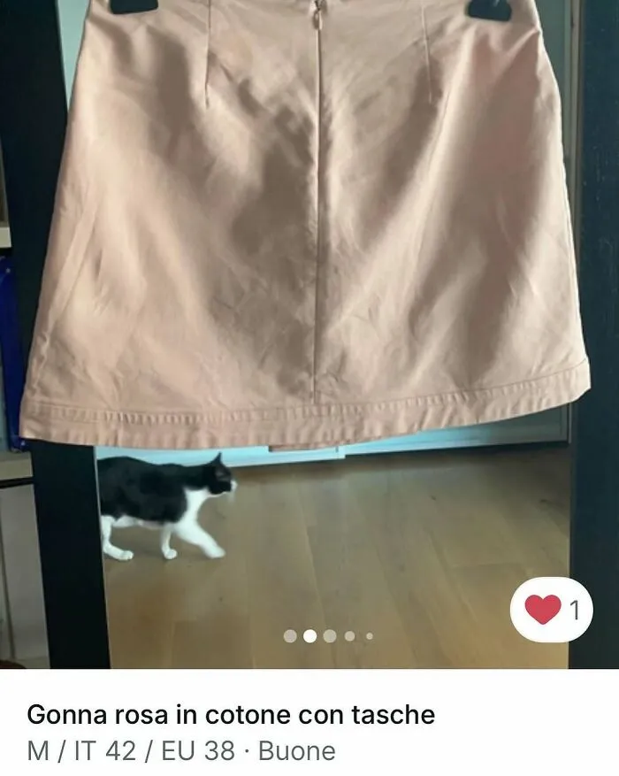 Black and white cat walking behind a pink cotton skirt in a cozy home setting for Vinted ads.