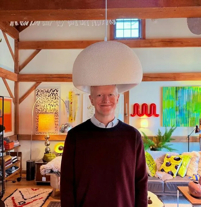 Tall man standing under a low hanging lamp in a colorful living room, illustrating common struggles for tall people.