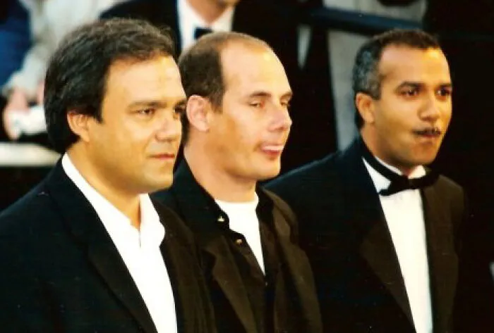 Three men in formal attire posing together, illustrating the concept of local inside jokes shared among people.
