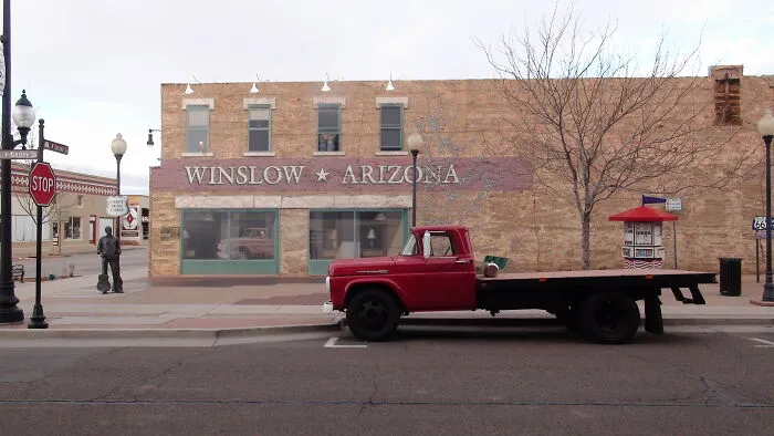 Red vintage truck parked in front of a Winslow Arizona building, illustrating disappointing tourist attractions locals still don’t get.