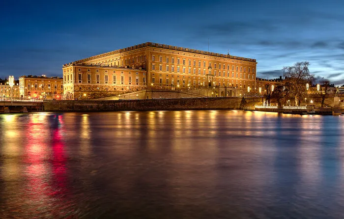 Historic tourist attraction lit at night with reflections on river, showcasing a disappointing tourist spot locals still don’t get.