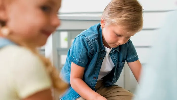 Young boy looking down thoughtfully in a casual setting, illustrating a scene from all you can eat buffet experiences.
