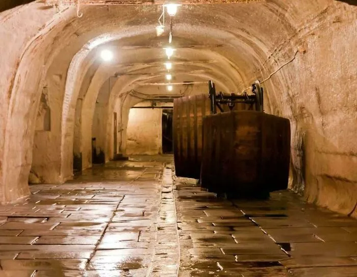 Underground tunnel with old barrels and dim lighting, representing disappointing tourist attractions locals still don’t get.