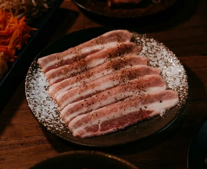 Raw seasoned pork slices on a plate illustrating cultural differences in what is normal but offensive elsewhere.