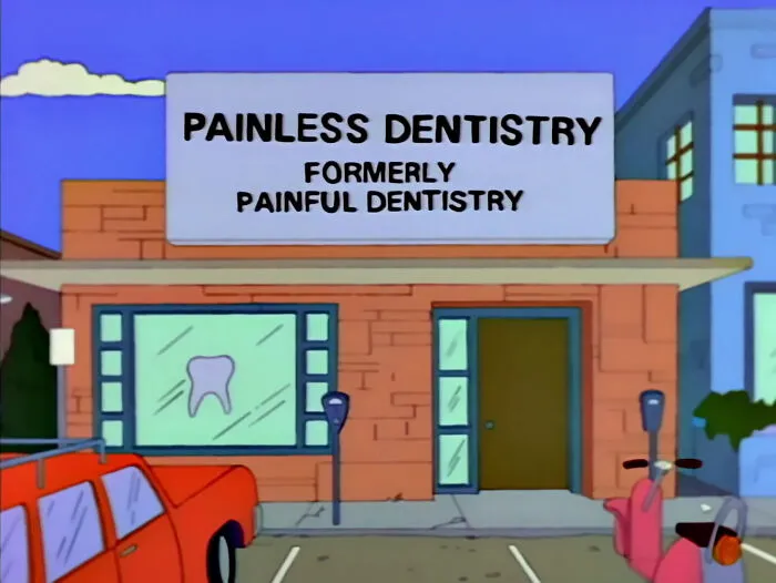 Simpsons sign reading painless dentistry formerly painful dentistry outside a brick building with parked cars nearby