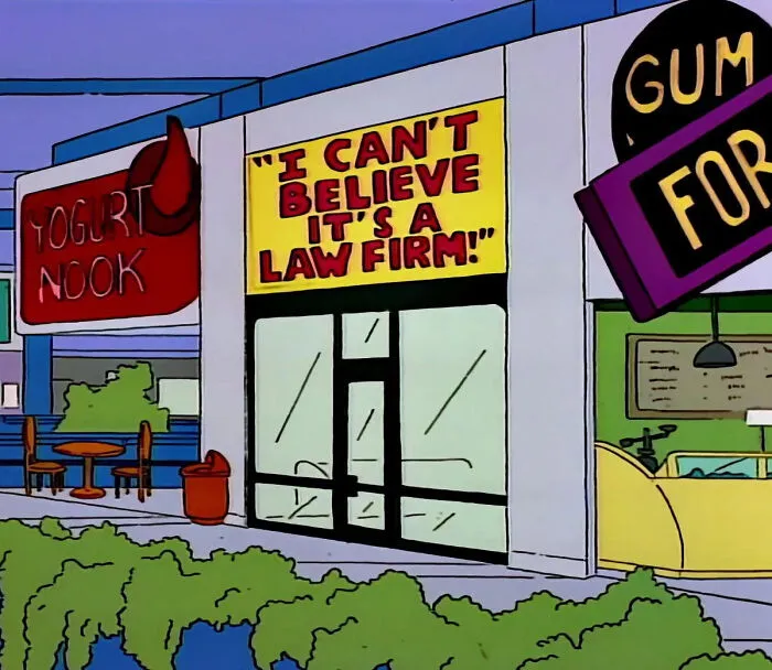 Simpsons scene showing a storefront sign that humorously reads I can't believe it's a law firm.